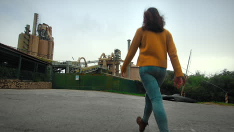 young girl roaming around a factory in a cloudy day