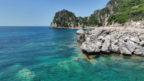 Aguas-Cristalinas-Del-Mar-Jónico-Acariciando-Las-Costas-Rocosas-De-La-Isla-De-Corfú-Bajo-Un-Cielo-Soleado