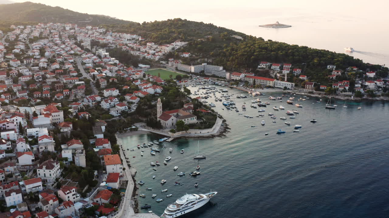 vista panorámica de la ciudad de hvar al amanecer con barcos y yates de lujo flotando en el mar adriático en croacia