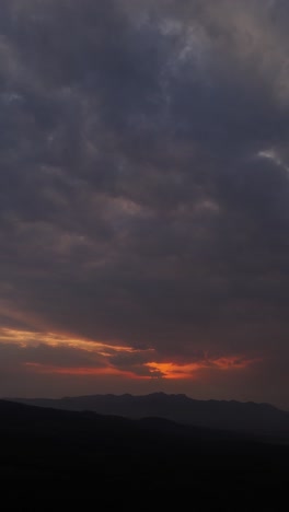 a dramatic vertical cloudscape at sunset with vibrant red sunlight piercing through the horizon.