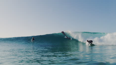 Slow motion view of surfer at golden hour in the morning as rider carves between lineup, backlit spraying and gliding on surface