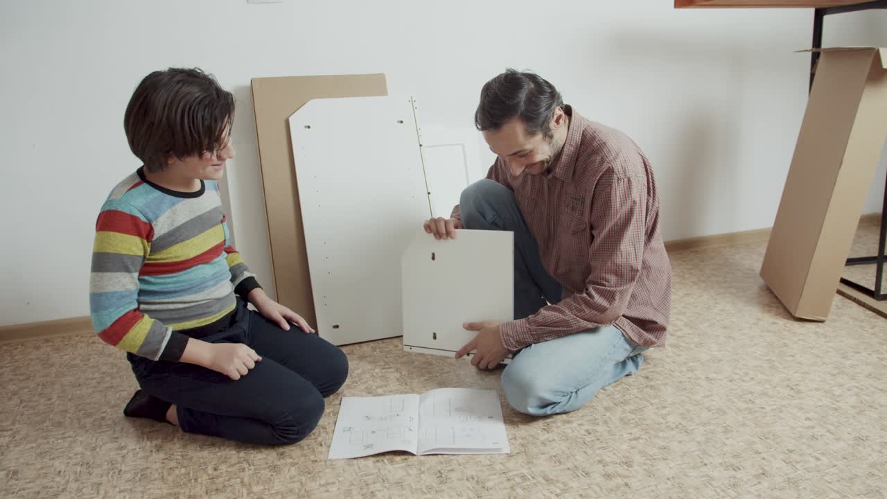 un adolescente positivo ayuda a su padre a montar muebles de acuerdo con las instrucciones. pasatiempo conjunto de padre e hijo. ahorro del presupuesto familiar. compra a través de internet