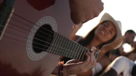 hombre tocando la guitarra para amigos al aire libre