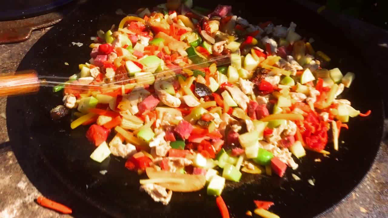 delicioso y colorido wok con tocino frito en una sartén grande, comida cocinada al aire libre en verano, cocina casera al aire libre