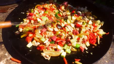 delicioso y colorido wok con tocino frito en una sartén grande, comida cocinada al aire libre en verano, cocina casera al aire libre