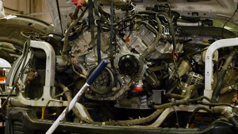 a mechanic pushes a engine into an empty engine bay cavity on a truck to get it ready to bolt into place