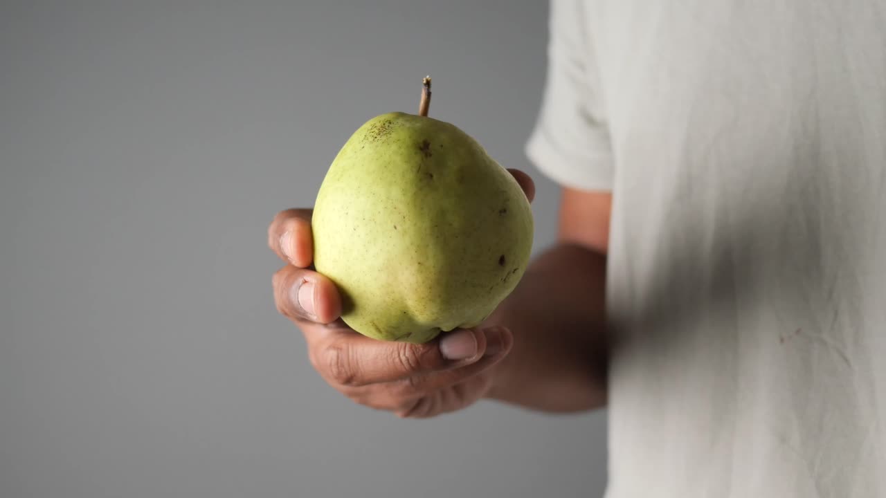 Close-up of a Person's Hand Holding a Fresh Green Pear
