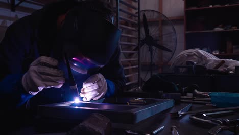 Close-up-of-modern-blacksmith-using-bright-heat-of-welding-machine-to-bind-frame