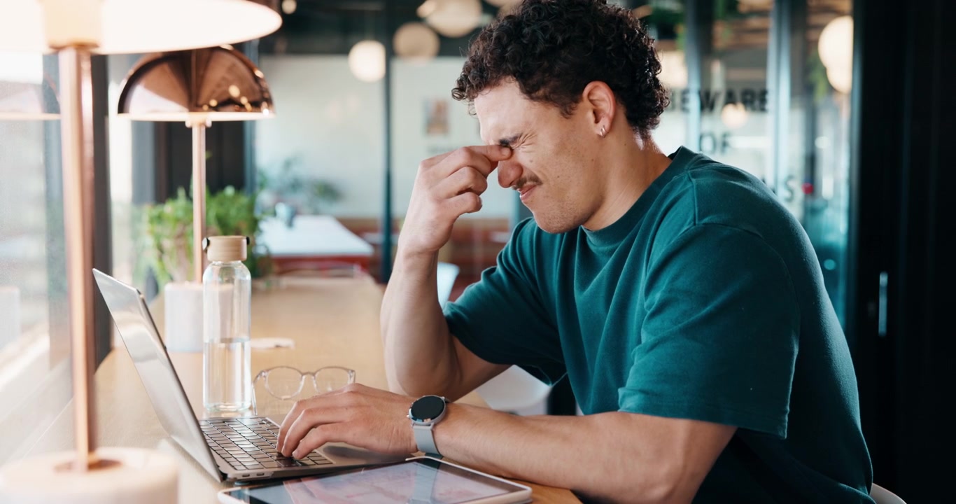 Stressed Young Man Working on Laptop in Modern Office