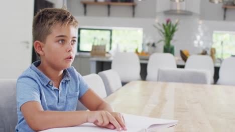 caucasian boy sitting at table and reading braille, slow motion