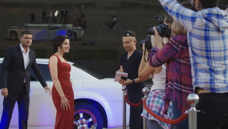 celebrity on red carpet signing autographs and posing for paparazzi