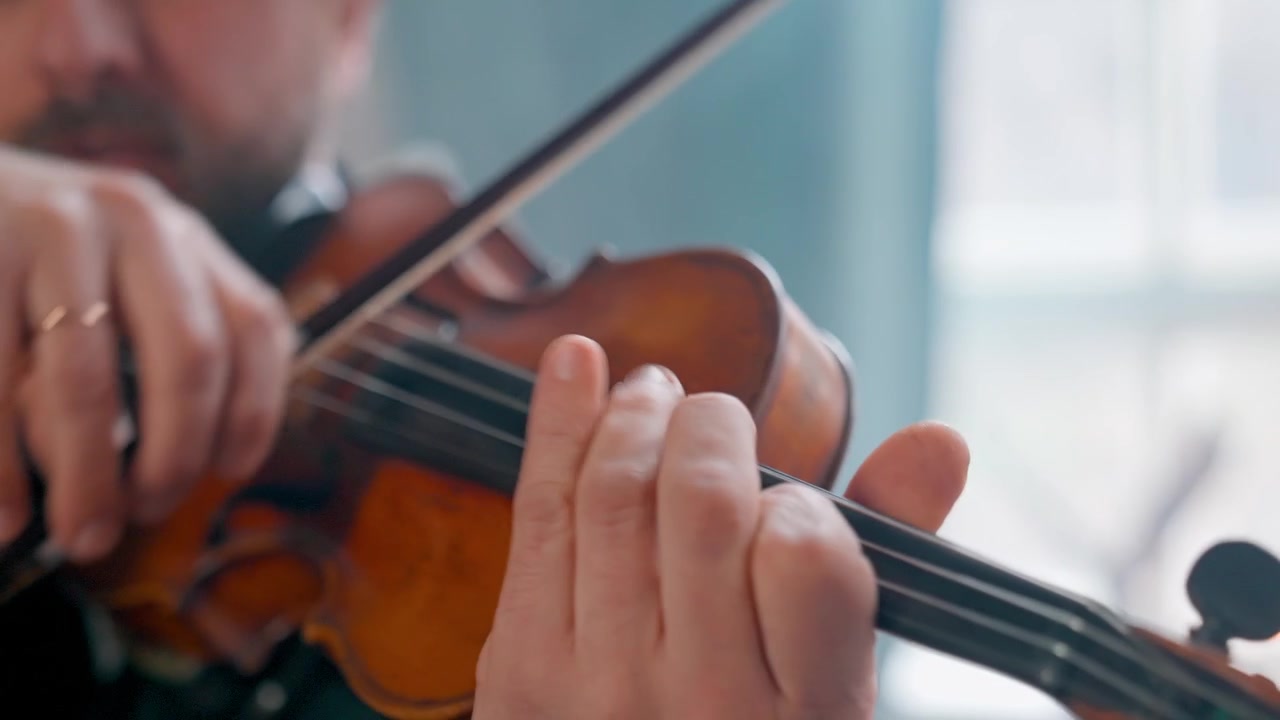 Primo piano di un uomo in abito formale che suona il violino