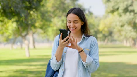 chica india feliz desplazándose por el teléfono