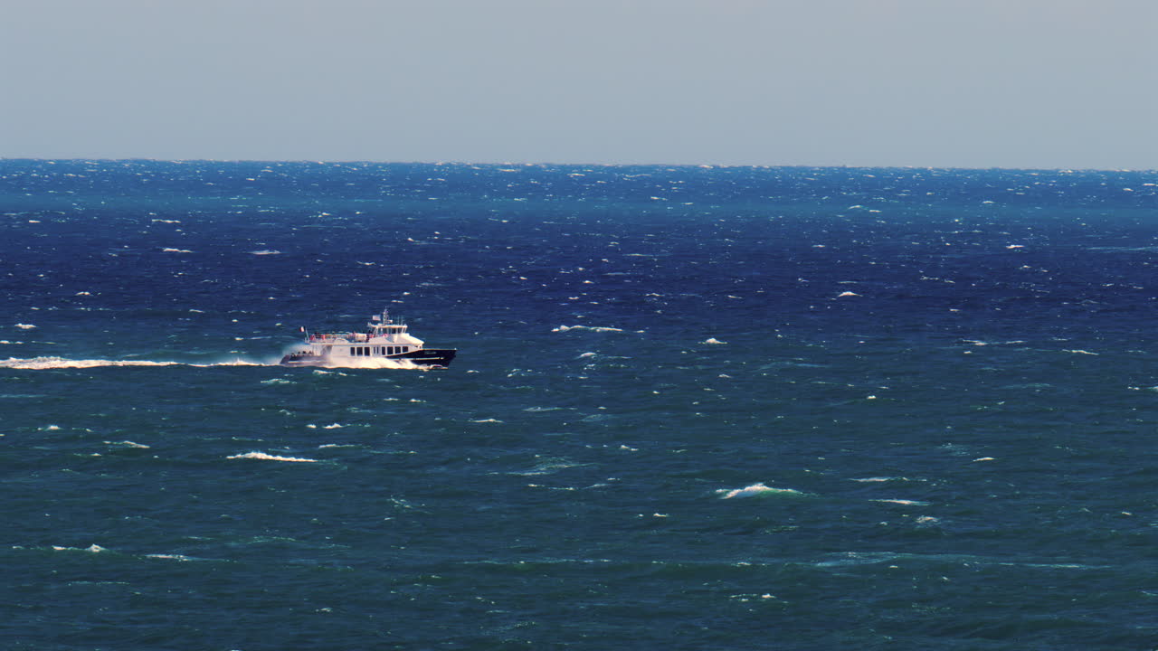 Nice, France - March 17, 2025: Distant view of a boat moving on the blue sea in daylight