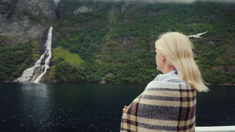 Eine-Frau-Mit-Einer-Tasse-Tee-In-Der-Hand-An-Bord-Eines-Kreuzfahrtschiffes-Blickt-Auf-Die-Wunderschönen-Berge-Der