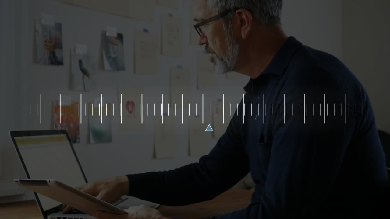 Man using tablet while typing on laptop in home business workspace, showing floating data charts