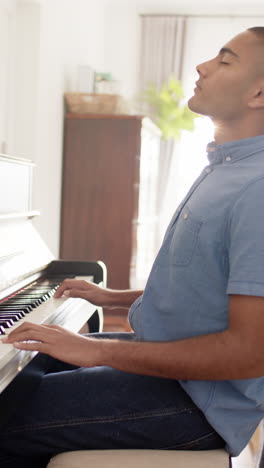 Vertical video of anglo indian man playing piano at home, slow motion