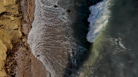 Sea-waves-and-turbulent-water-splashing-on-rocky-coastline-of-Mediterranean,-top-down-view