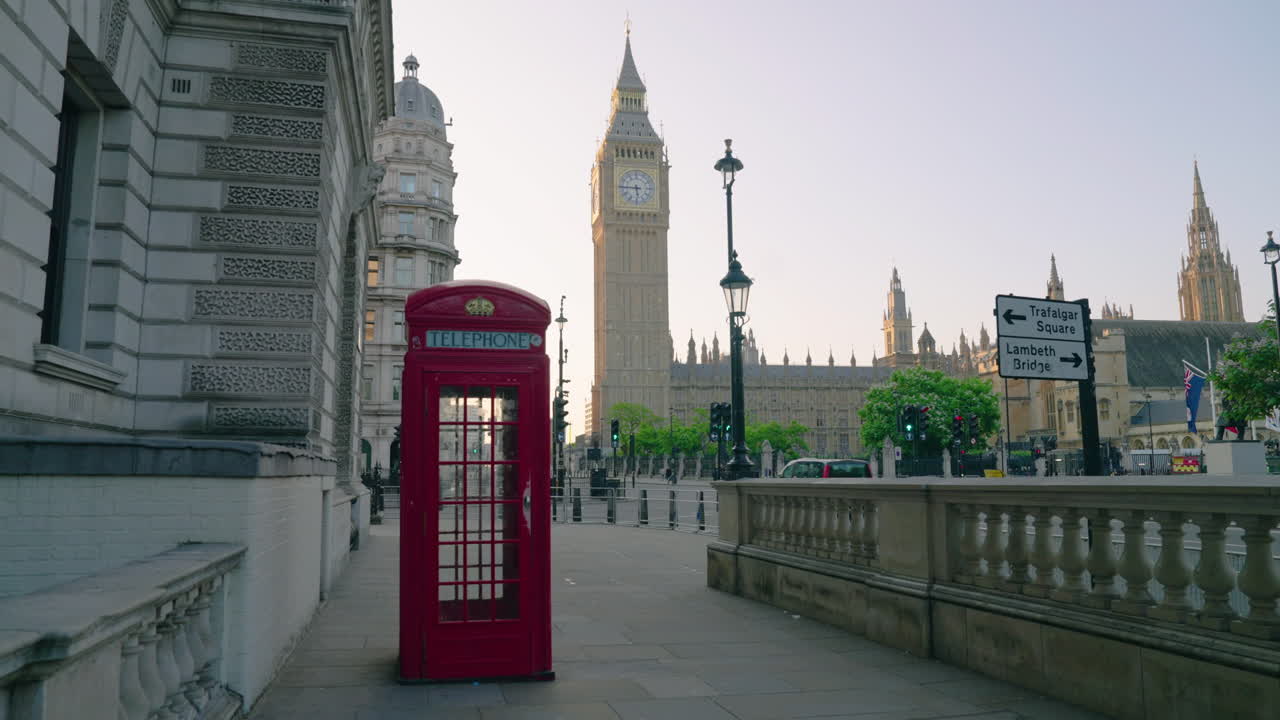 Woman In Red Dress Walking On The City Street With The Iconic Telephone Booth And Big Ben Clock Tower In London, England, UK. Static Shot