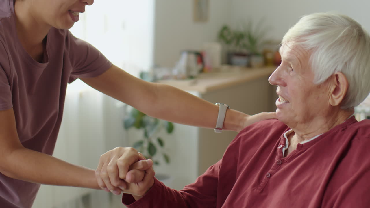 Woman Holding Hands and Talking with Old Man in Wheelchair