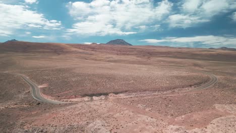 Coche-Pasando-Por-Una-Carretera-En-El-Desierto-Chileno-Con-Volcanes-En-El-Fondo