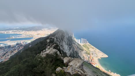 view from the rock of gibraltar surrounded by thick white clouds and the ocean in the background