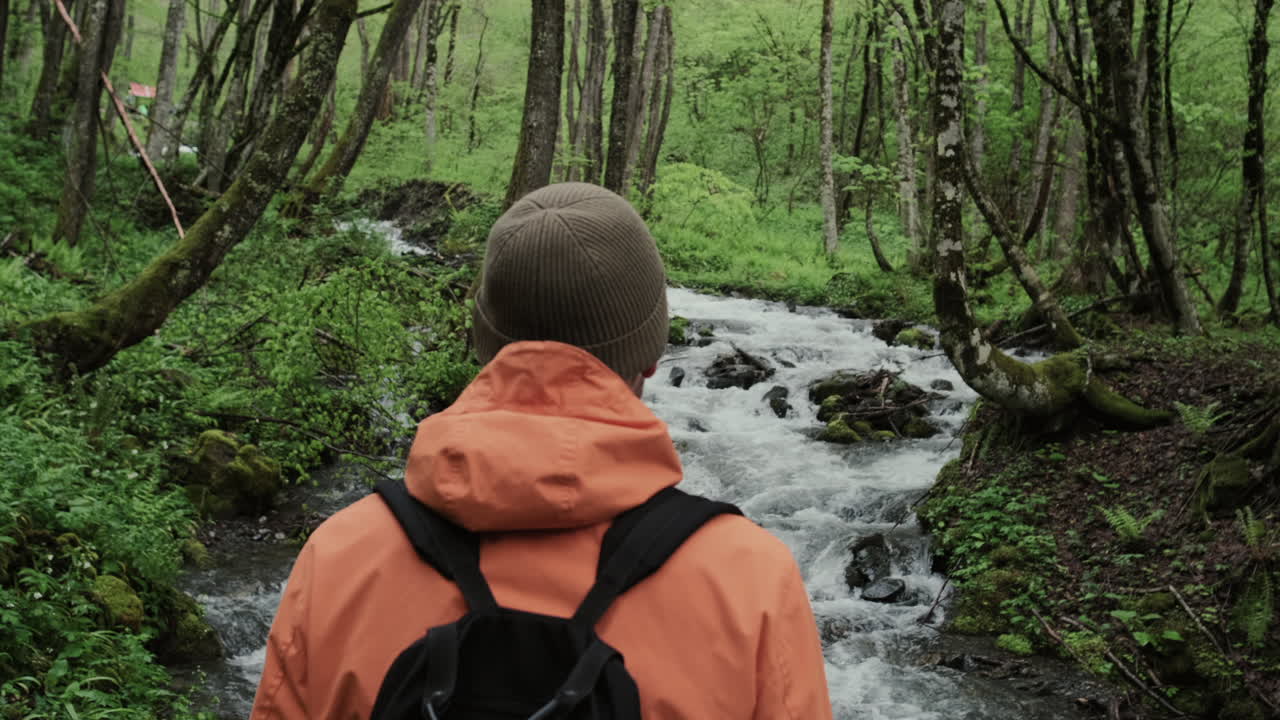 hombre caminando en un arroyo del bosque