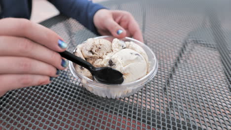 close up shot of womans hand eating ice cream on metal table