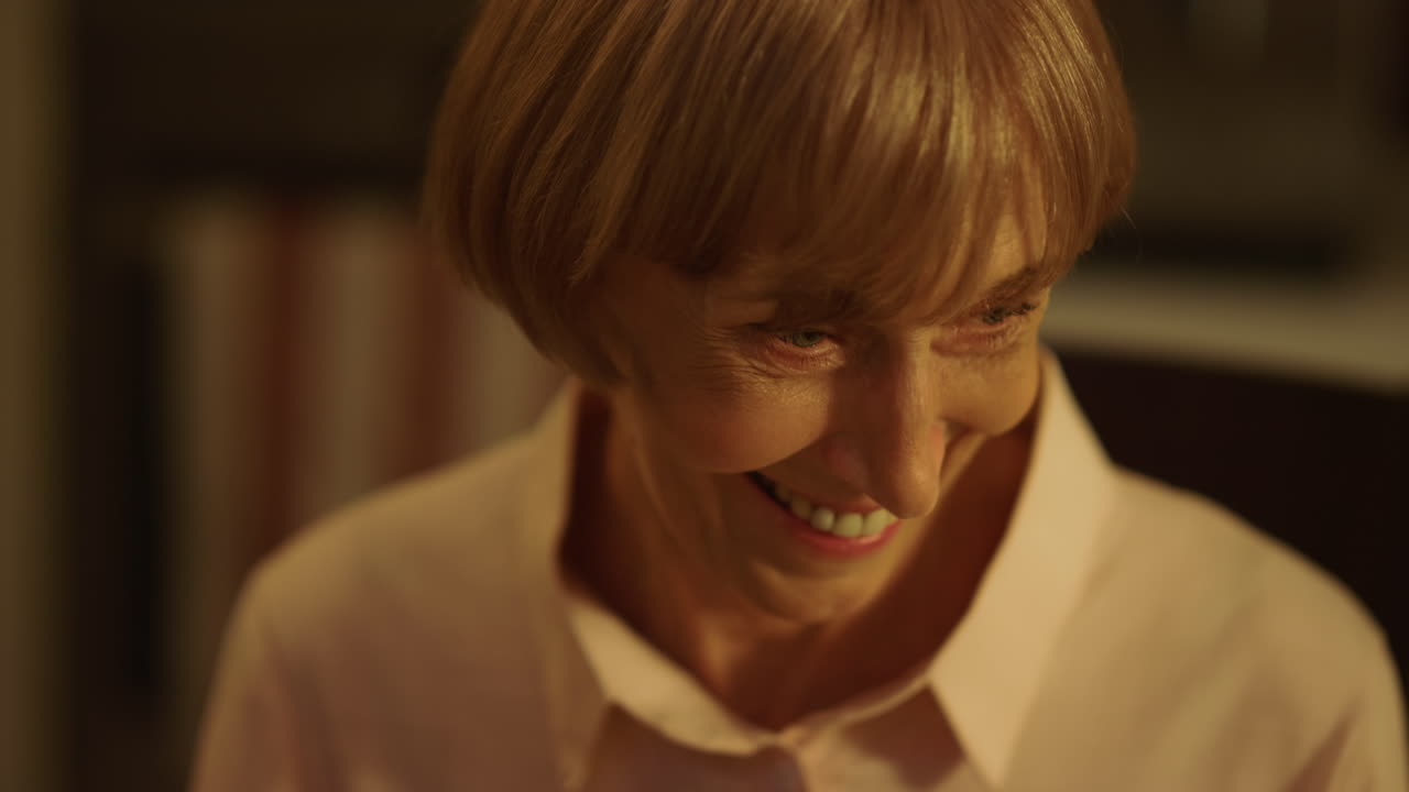 Mature woman laughing at camera. Smiling lady looking down