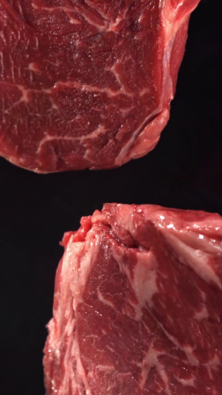 Raw Beef Steaks Falling in Slow Motion Against a Black Background