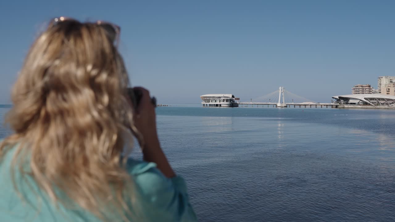 Woman takes photo of bridge in Durres, Albania, close pan from behind