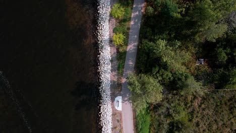 Man-biking-through-the-bottom-of-the-frame-through-to-the-top,-Aerial-Bird's-eye-view-of-man-using-the-Muskegon-Bike-Path