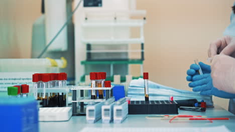 two nurses are working with test tubes in medical laboratory. scientists women in gloves fill the vials with liquid and put them into a rack on a sterile table.