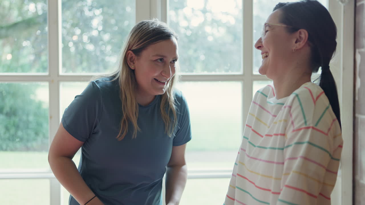 Two women talking near a window