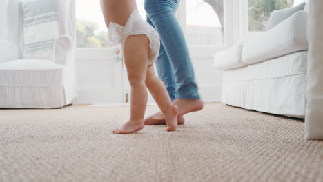 bebé dando sus primeros pasos niño pequeño aprendiendo a caminar con la madre ayudando suavemente al bebé enseñando al niño en casa la confianza de la maternidad