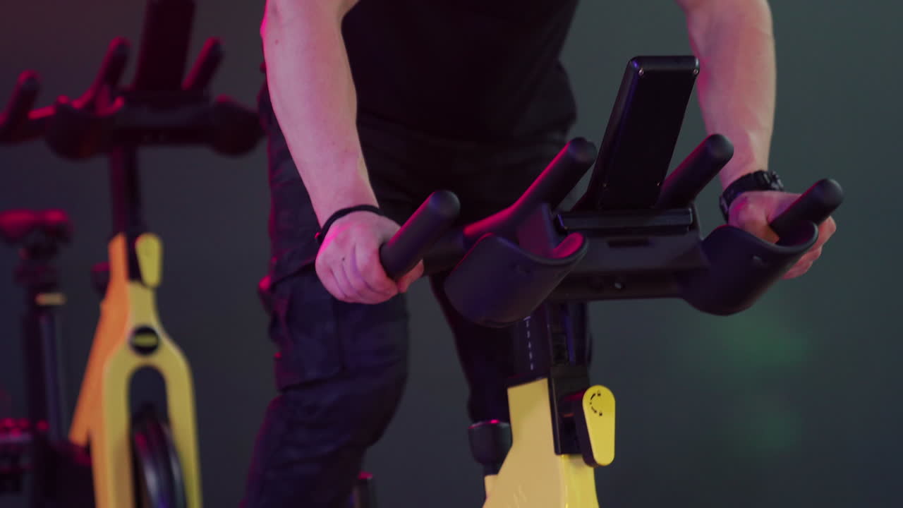 Muscular man training hard in gym. Strong man training cardio exercise on fitness bike