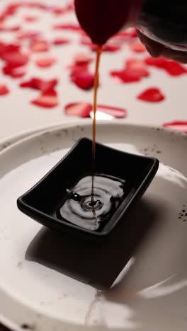 soy sauce being poured over food with rose petals