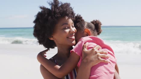 Lächelnde-Afroamerikanische-Mutter-Mit-Tochter,-Die-Sich-Am-Sonnigen-Strand-Umarmt