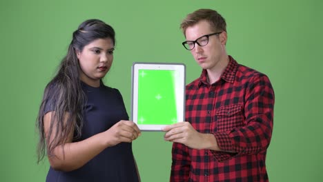 joven pareja de negocios multiétnica juntos contra un fondo verde
