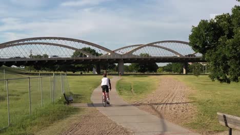 drone video of cyclist riding bike path near trinity river fort worth texas and 7th street bridge