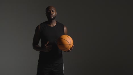 Studioporträtaufnahme-Eines-Männlichen-Basketballspielers,-Der-Vor-Dunklem-Hintergrund-Den-Ball-Von-Hand-Zu-Hand-Wirft-1