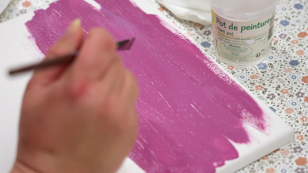 Person applying purple shades to a canvas during a painting activity
