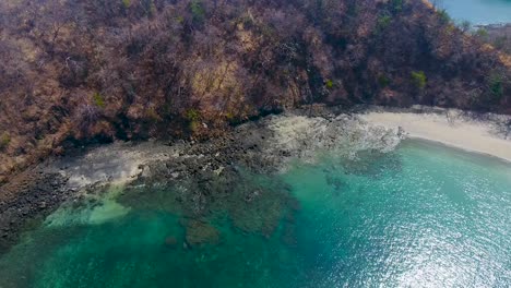 aerial video looking down on a very rough rocky outcropping that dead trees and rocky cliffs in costa rica