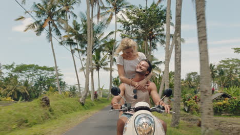 travel couple riding scooter on tropical island happy woman celebrating with arms raised enjoying fun vacation road trip with boyfriend on motorcycle ride