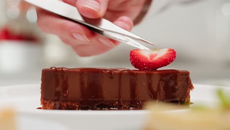 chef placing strawberry on chocolate cake