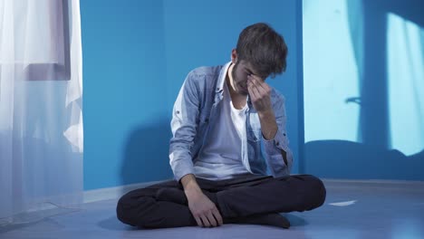 바닥에 앉아 있는 남자가 울고 있다. 절망하고 있다.