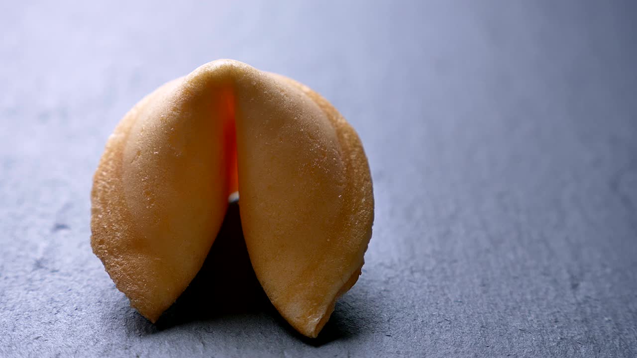 회색 테이블 배경에서 천천히 회전하는 행운의 쿠키의 을 둘러싼 클로즈업.