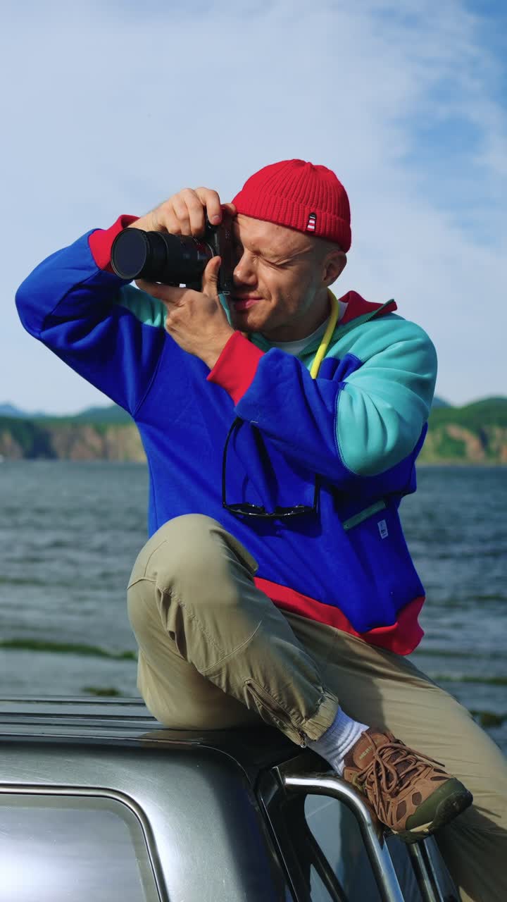 Man Sitting on Car Roof Taking Photos of Scenic Landscape