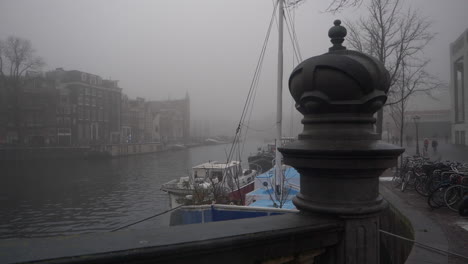 house boats moored in a canal in amsterdam on a foggy day