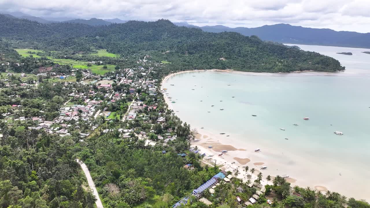 Port Barton, Palawan. Aerial wide of settlement and bay with boats. Moody day, Philippines